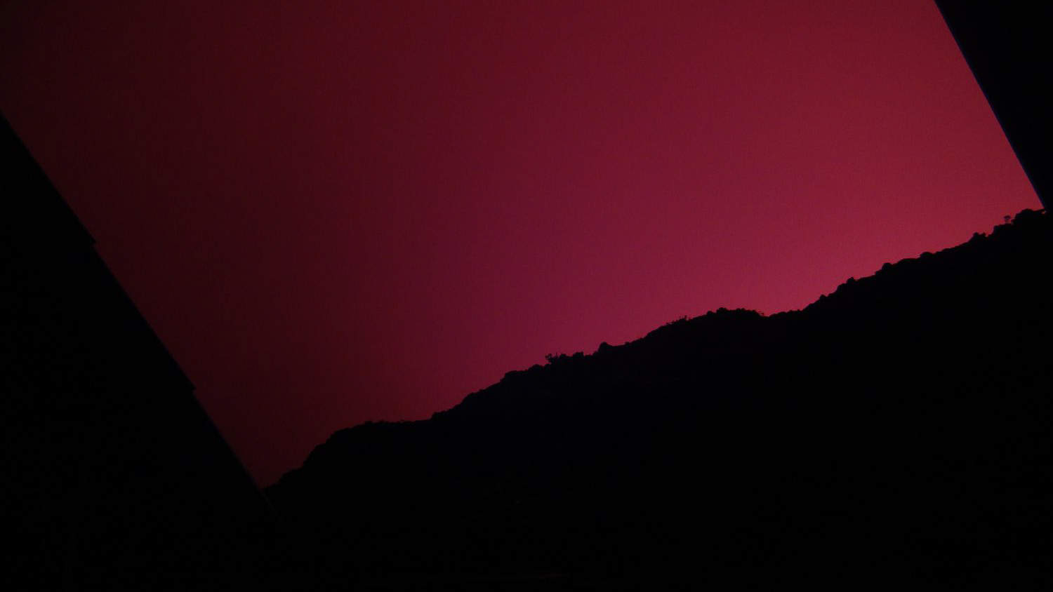 Rot erleuchteter Himmel über den Hütten am Kraterrand