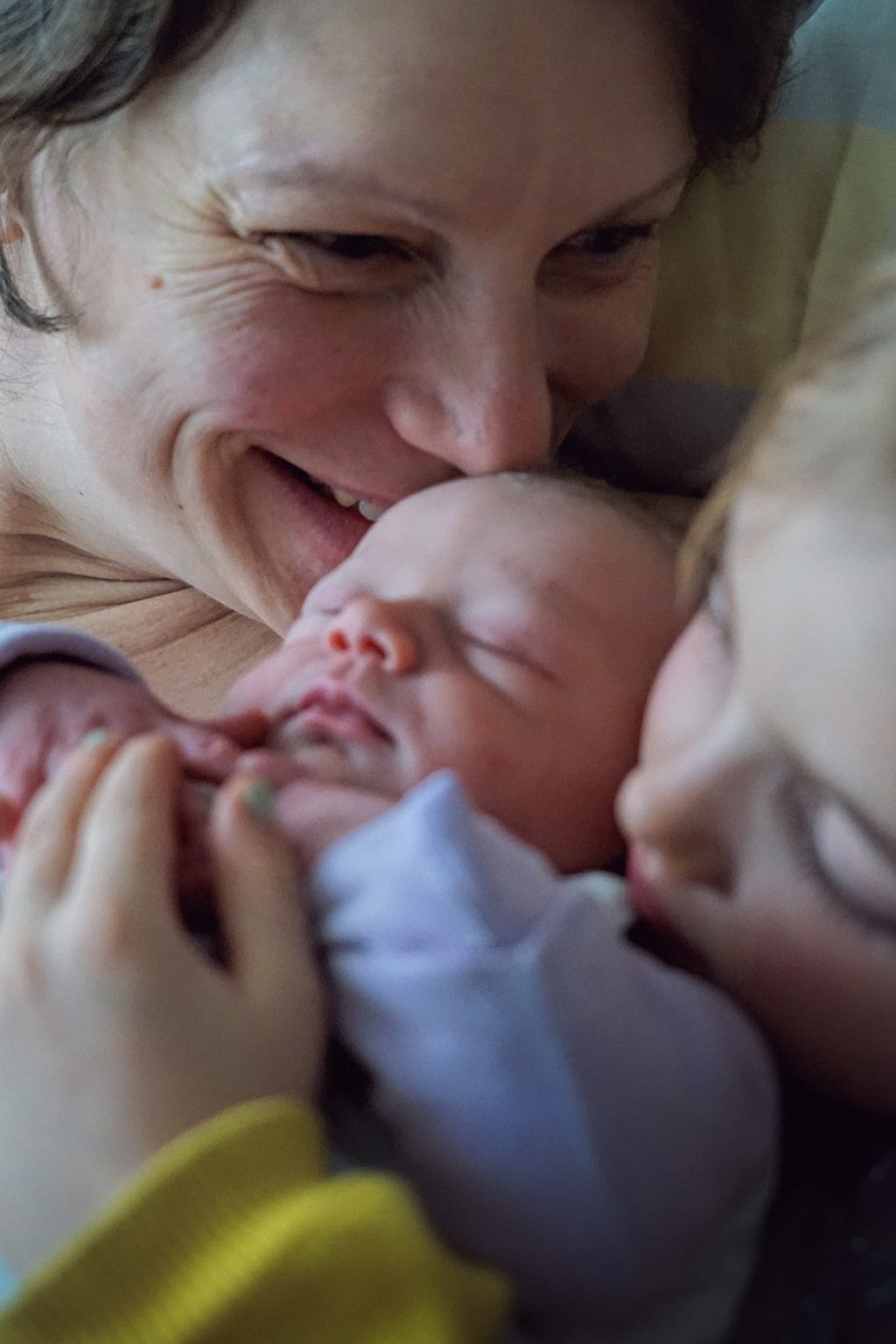 LIFE-for-FIVE-Elternzeit- Mama kuschelt mit Neugeborenem und Tochter