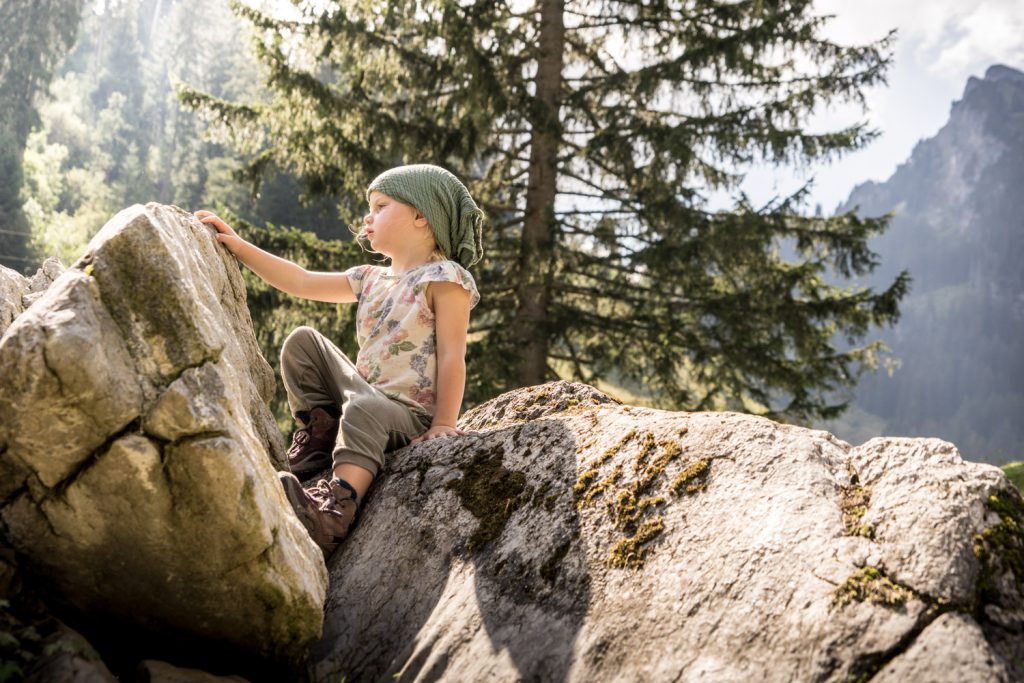 LIFE-for-FIVE-fernweh-Mädchen sitzt stolz zwischen zwei Felsen in den Bergen