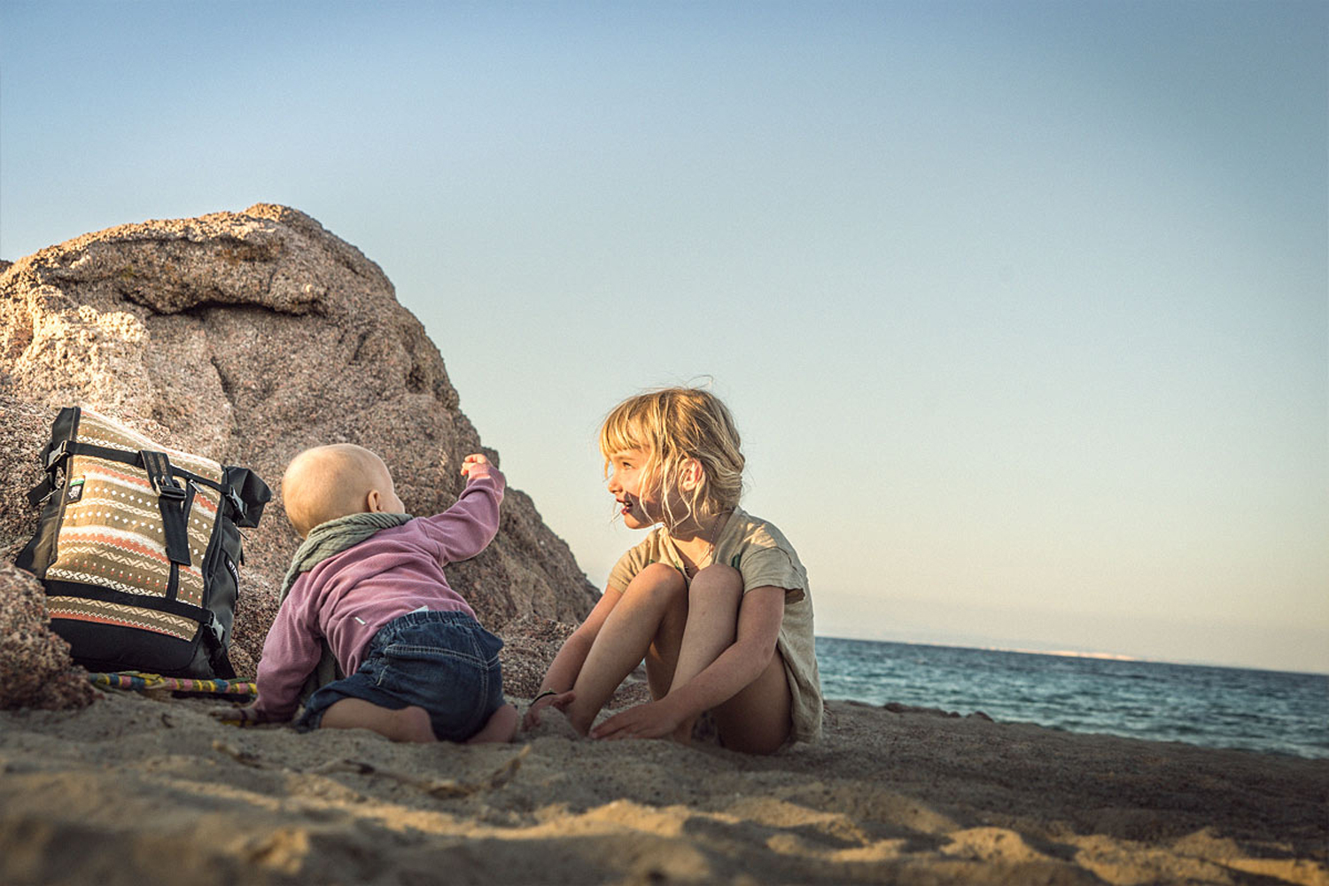 LIFE-for-FIVE-Sardinien-mit-Kindern-Unser Baby mit ihrer grossen Schwester am Strand vor einem kleinen Felsen.