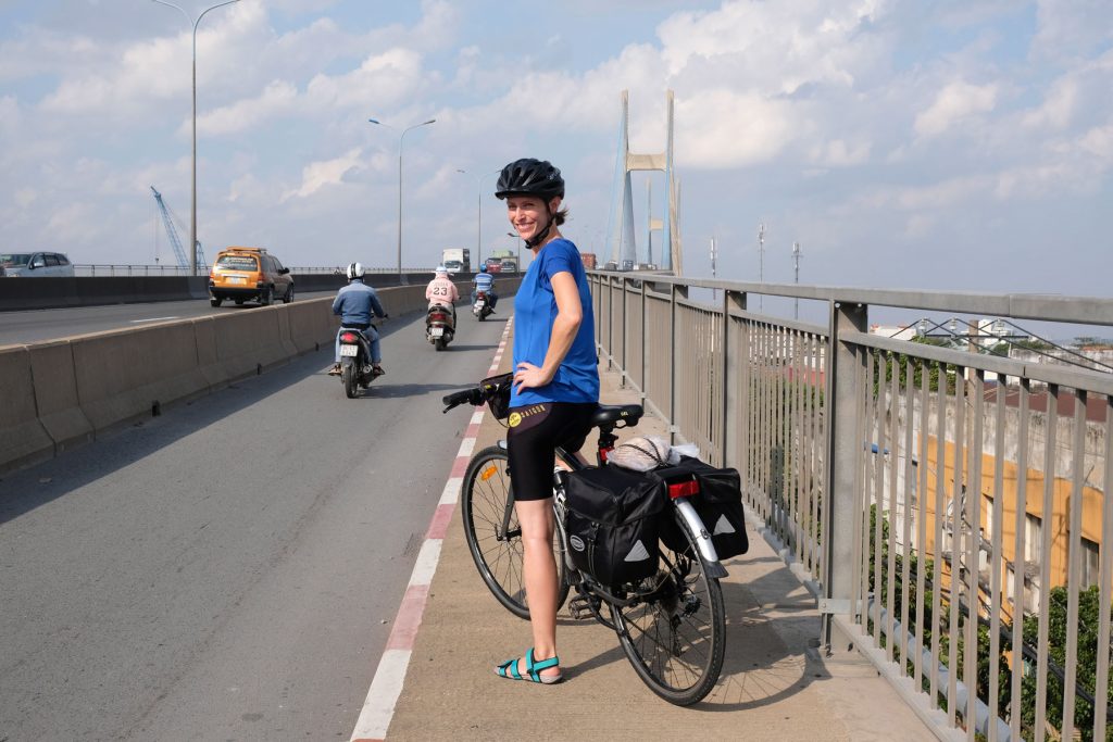 Leo steht mit ihrem Fahrrad auf einer Brücke in Ho-Chi-Minh-Stadt.