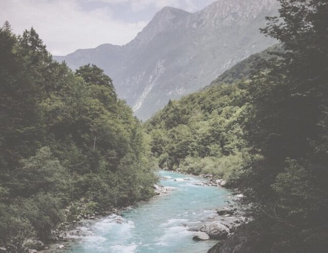 Fluss mit smaragd blauem Wasser beim Kozjak-Wasserfall, umgeben von dichtem Grün.