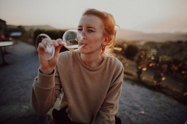 Autorin Magda Lehnert mit einem Glas Wein im Sonnenuntergang – stimmungsvolle Szene aus Slowenien.
